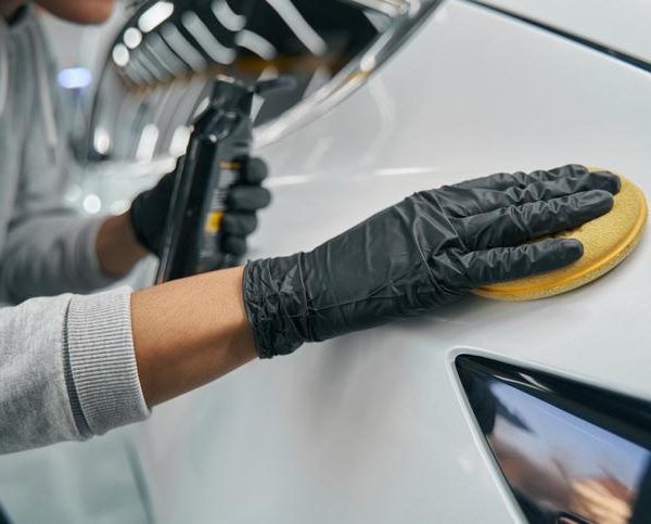 An auto detailing professional preparing a car for the showroom after automotive school