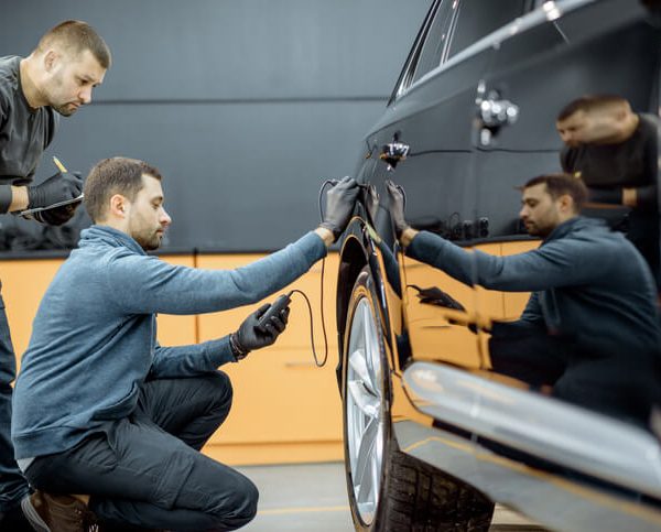 Student in auto body training examining vehicle for scratches