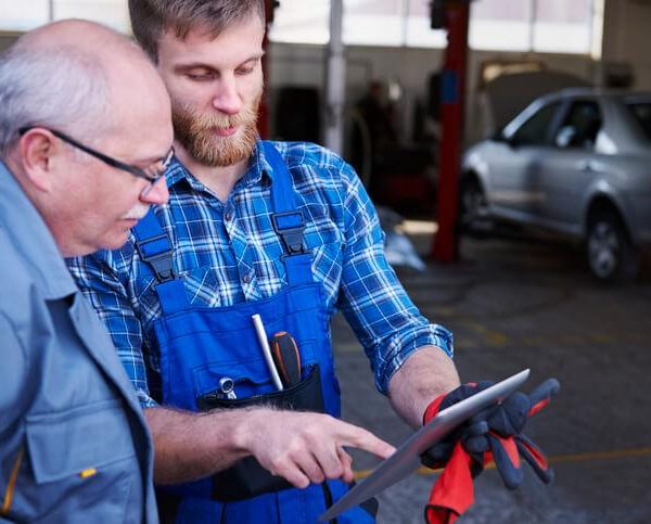 A student in automotive school showing a client more information on a tablet.