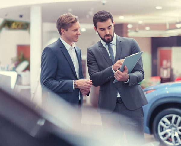 An automotive training grad managing a car dealership