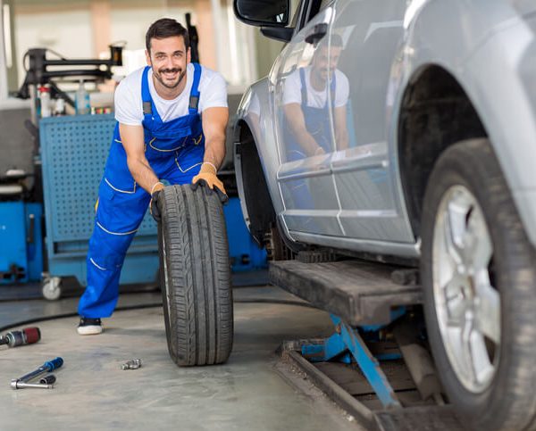 An auto parts specialist working on a tire in a warehouse after auto body training
