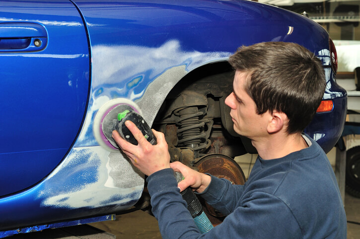 auto body training grads examining a car’s exterior