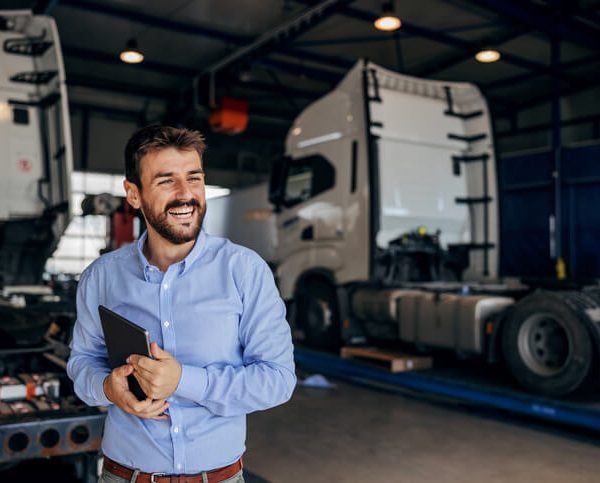 A dispatch training graduate posing in a garage full of trucks