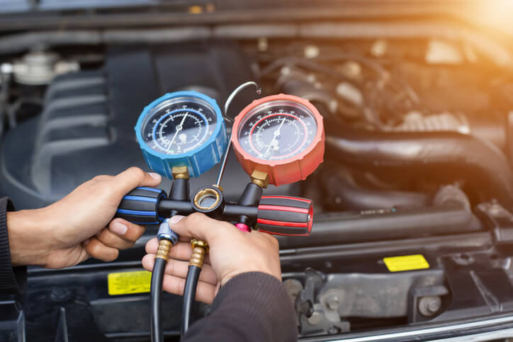 A mechanic checking for Freon leaks in automotive air conditioning training