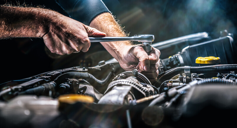 An auto mechanic working on a vehicle’s engine after graduating from auto mechanic school