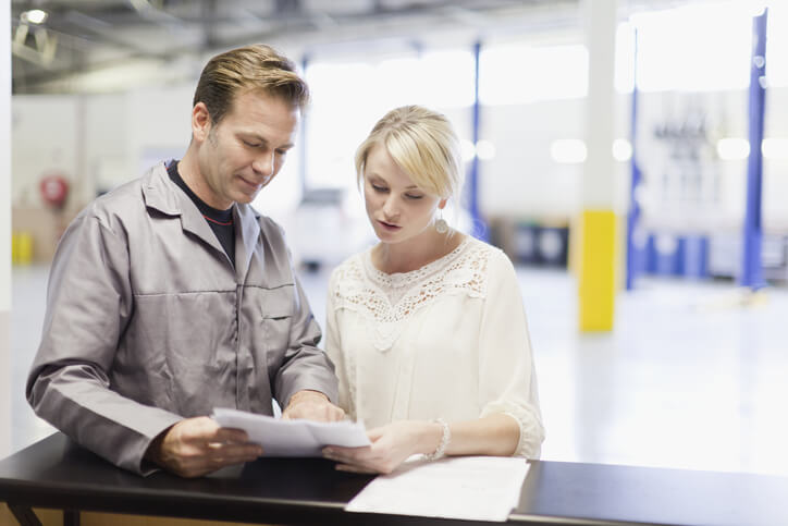 An auto mechanic interacting with a female customer after graduating from auto mechanic school