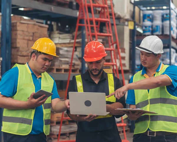 A male dispatcher confirming details with two colleagues at a warehouse after completing his dispatch training