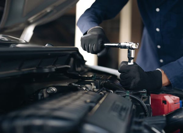 A professional auto mechanic performing maintenance on a car, preparing for a successful future as a shop owner after auto mechanic training.