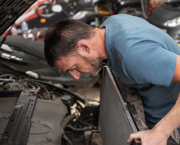 An automotive training student working on a vehicle's cooling system