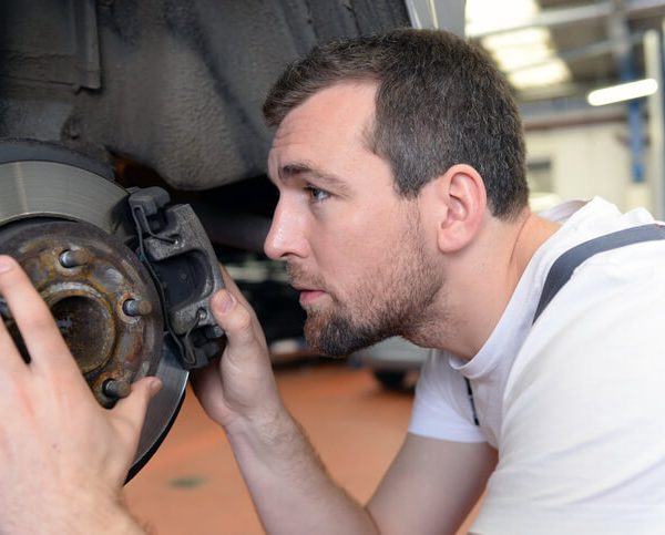 An automotive training student inspecting brake calipers