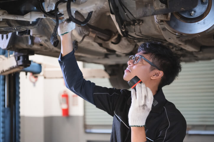 A Mechanic inspecting a car's subframe in a garage