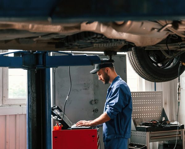 A modern auto mechanic using computer diagnostics on a vehicle in a high-tech garage