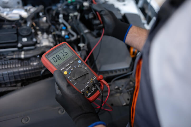 A CATI school student using a multimeter to test vehicle electronics