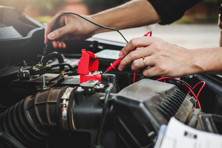 A student performing hands-on diagnostics during auto mechanic training in a fully equipped garage at CATI.