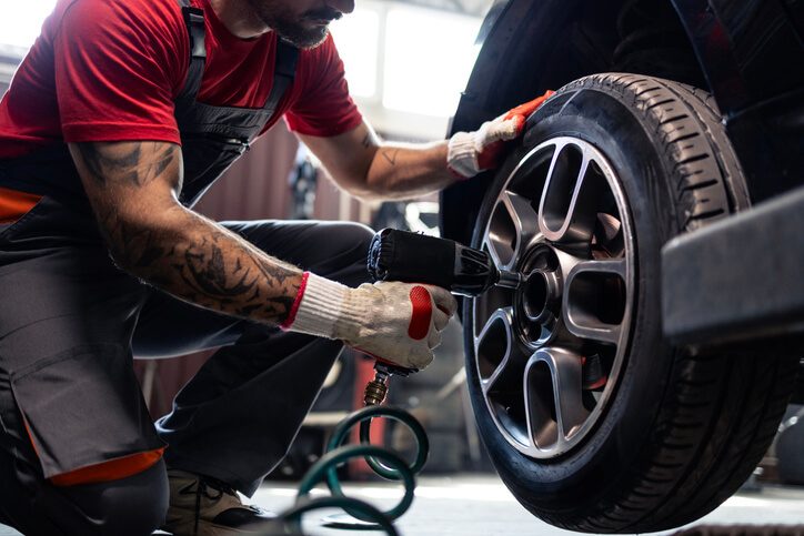 A student performing wheel maintenance with a power tool as part of hands-on auto mechanic training.