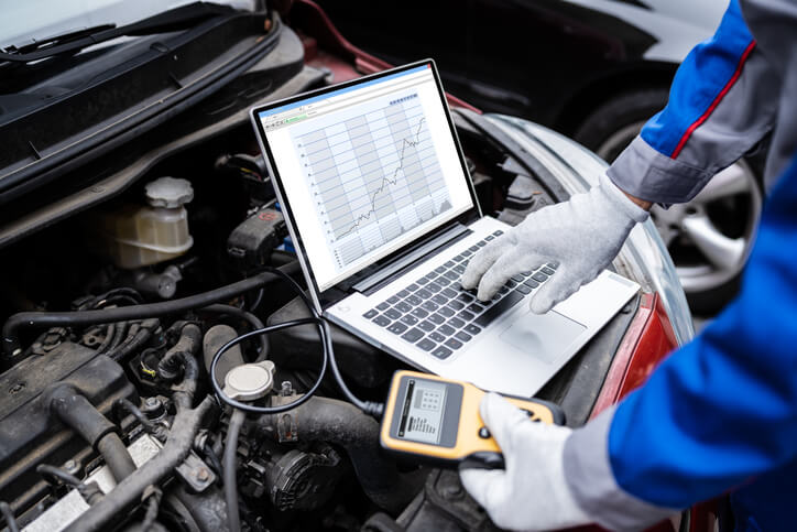 A specialist mechanic performing hybrid vehicle diagnostics after completing automotive training.