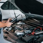 An auto mechanic student at CATI using a smart diagnostic scanner on a modern car