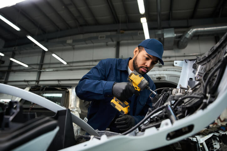 An auto mechanic trainee using ergonomic tools at a professional workstation during hands-on training