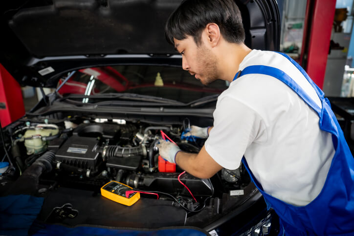 An auto mechanic technician using diagnostic tools during advanced automotive training.