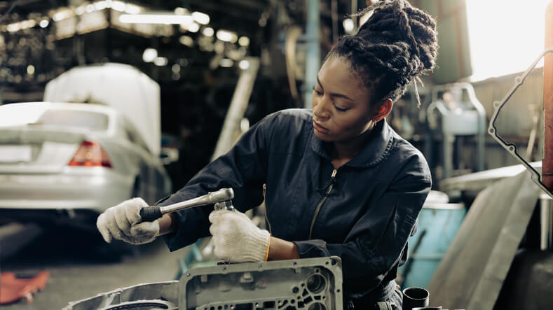 A student in auto mechanic training is tightening engine bolts during hands-on workshop practice