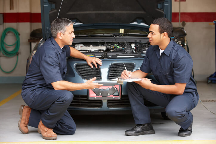 An automotive training instructor guiding a student during a repair session