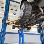 A student in auto mechanic training checking a vehicle during an inspection.