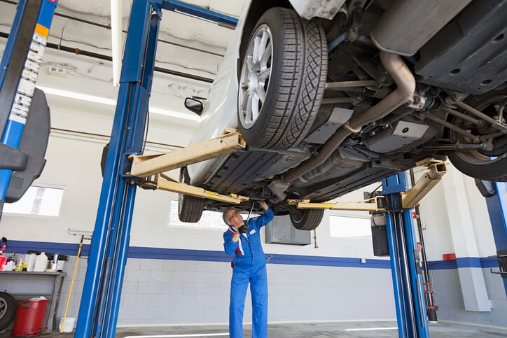 A student in auto mechanic training checking a vehicle during an inspection.