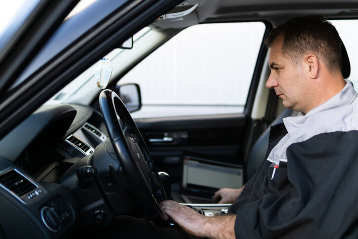 An auto mechanic is diagnosing car problems that only happen while driving during a road test, looking for car problems that only happen while driving