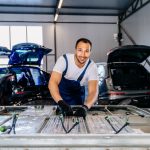 A technician in protective gloves is handling an EV battery pack in a workshop as part of EV battery recycling and safe removal procedures.