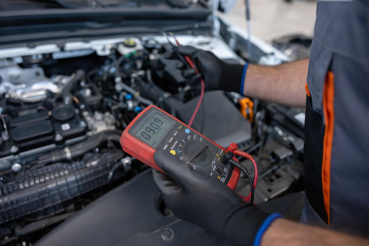 An automotive student is testing oxygen sensor wiring with a multimeter
