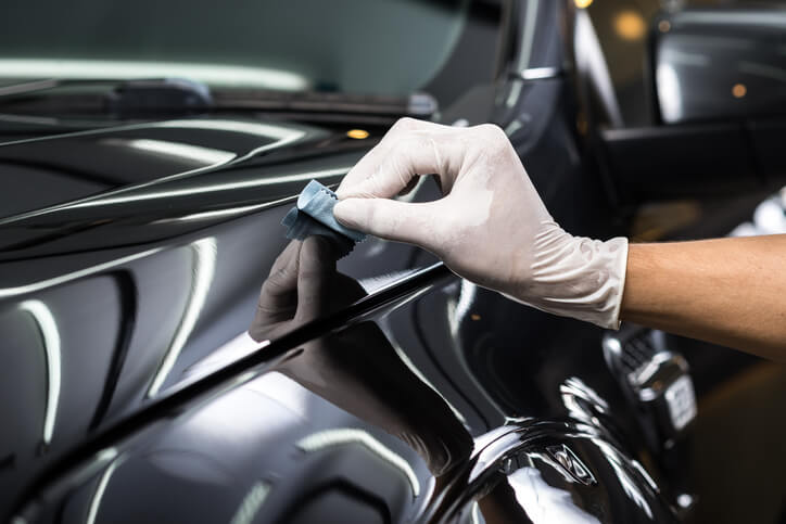A technician applying protective coating during car detailing
