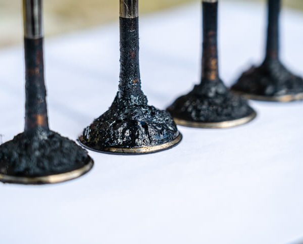 A row of Intake valves with heavy carbon buildup in a direct-injection engine