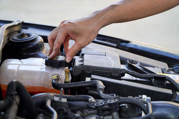 An automotive student inspecting a vehicle cooling system during hands-on training.
