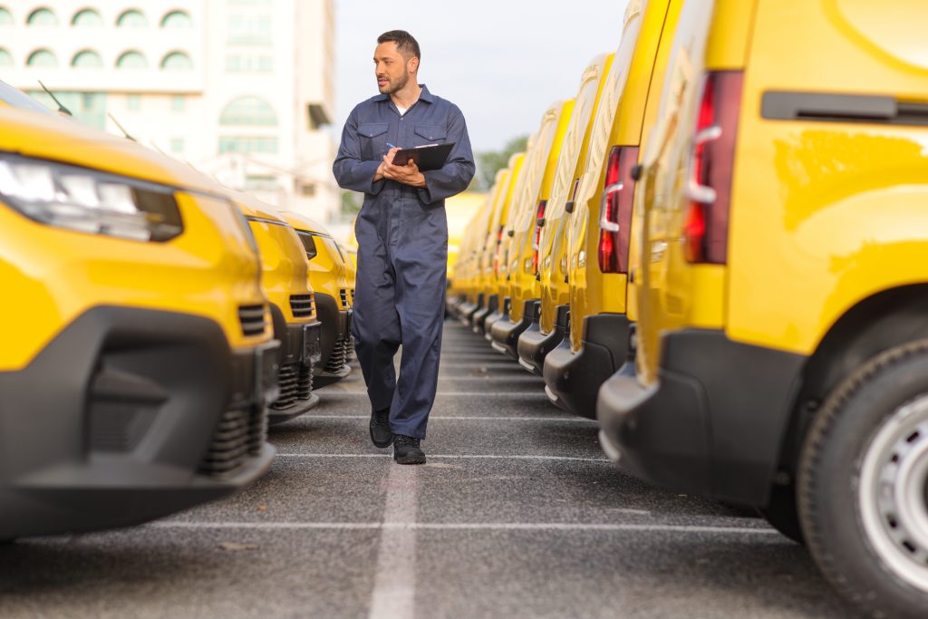 A technician inspecting multiple company vehicles in a fleet maintenance facility