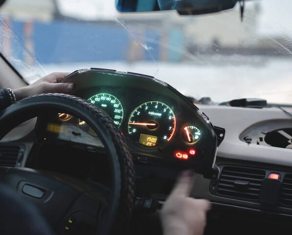A technician checking an electronic throttle light on a vehicle dashboard