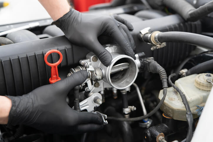 An automotive student is inspecting a throttle body during hands-on training