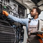 A fleet mechanic performing preventative maintenance on a commercial vehicle