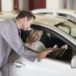 A service writer discussing vehicle concerns with a customer at an automotive service desk
