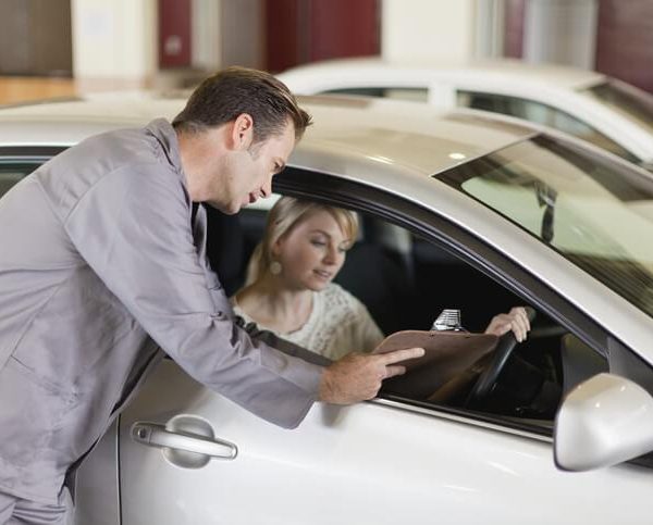 A service writer discussing vehicle concerns with a customer at an automotive service desk
