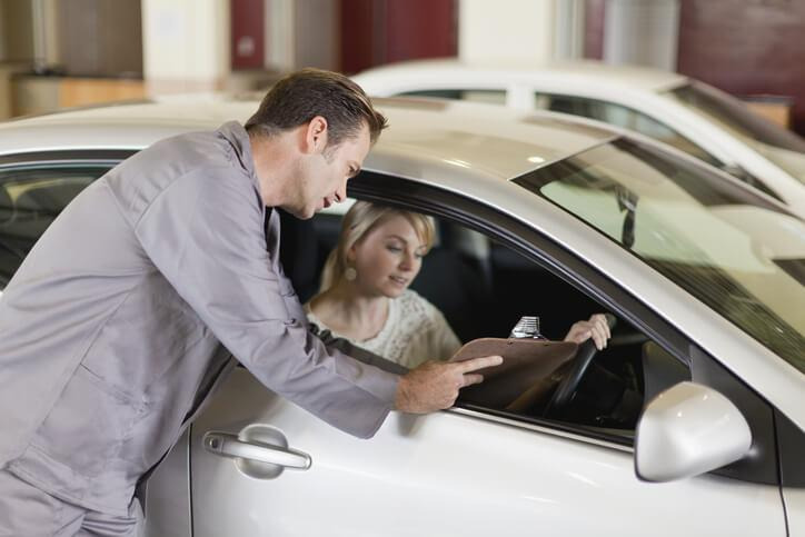 A service writer discussing vehicle concerns with a customer at an automotive service desk