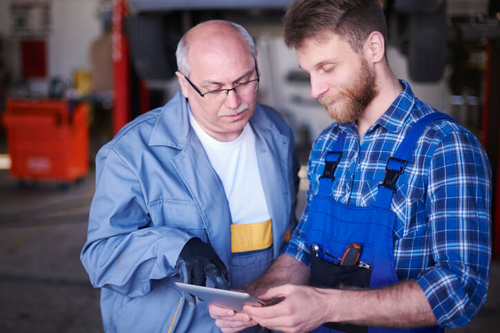 An automotive service advisor reviewing a repair order with a technician