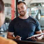 A service writer discussing vehicle repairs with a customer at a service counter