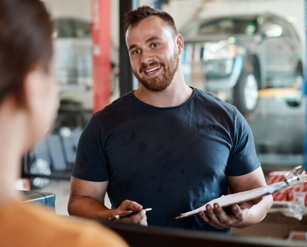 A service writer discussing vehicle repairs with a customer at a service counter