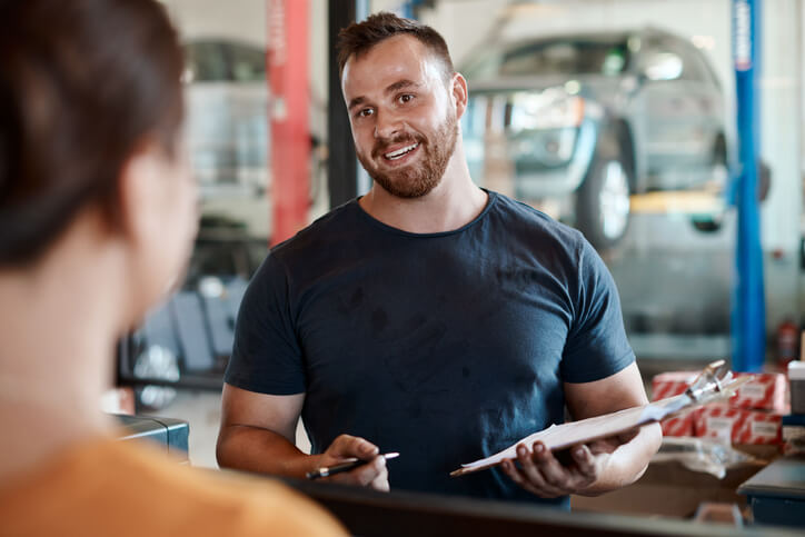 A service writer discussing vehicle repairs with a customer at a service counter