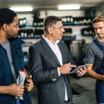 An automotive service manager discussing repair orders with technicians in a repair shop