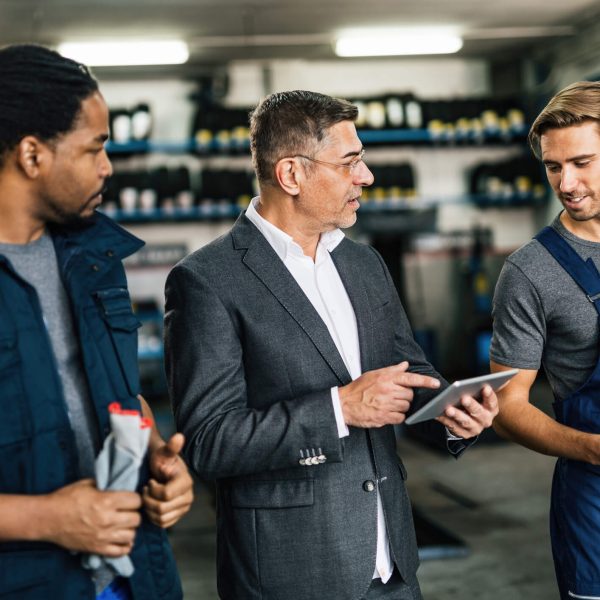 An automotive service manager discussing repair orders with technicians in a repair shop
