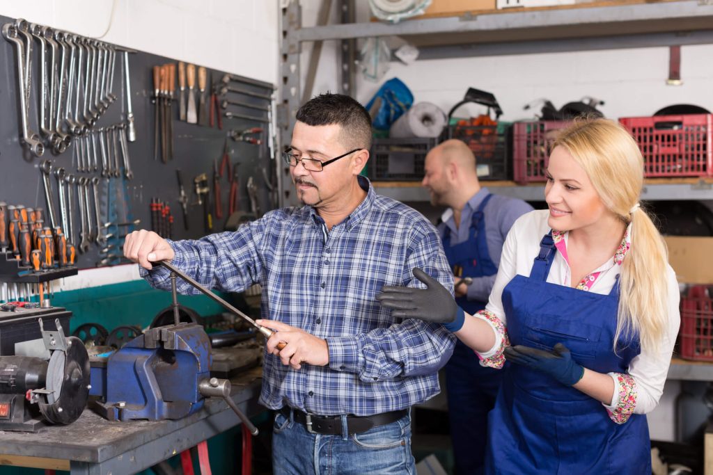 An instructor teaching beginner mechanics on proper tools and safety procedures