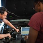 An automotive student learning vehicle diagnostics during hands-on shop training