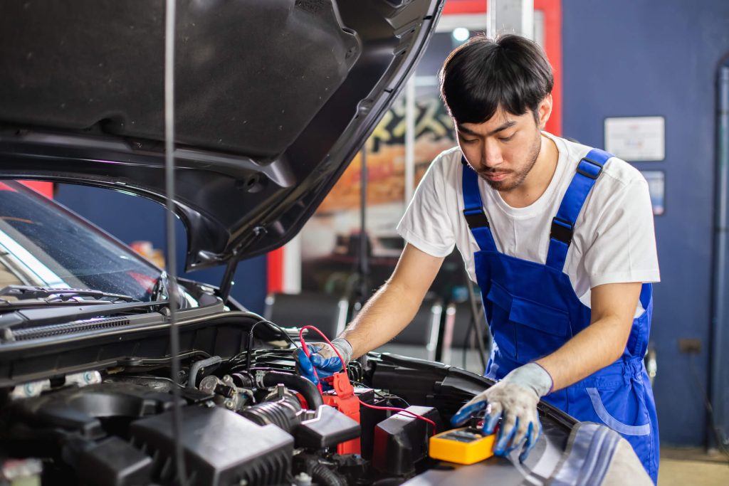 Student checking a vehicle battery during automotive diagnostics training