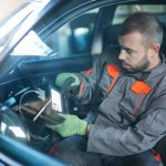 Automotive technician performing no-start diagnosis on a vehicle with a scan tool